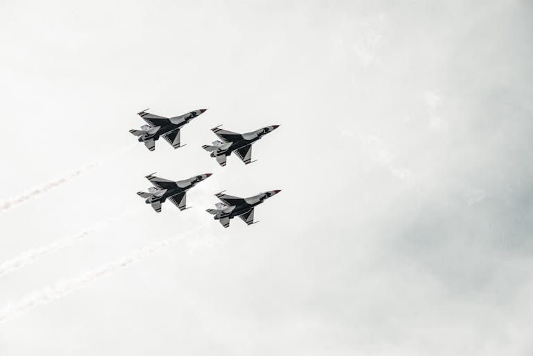 A squadron of fighter jets flying in formation against a cloudy sky.