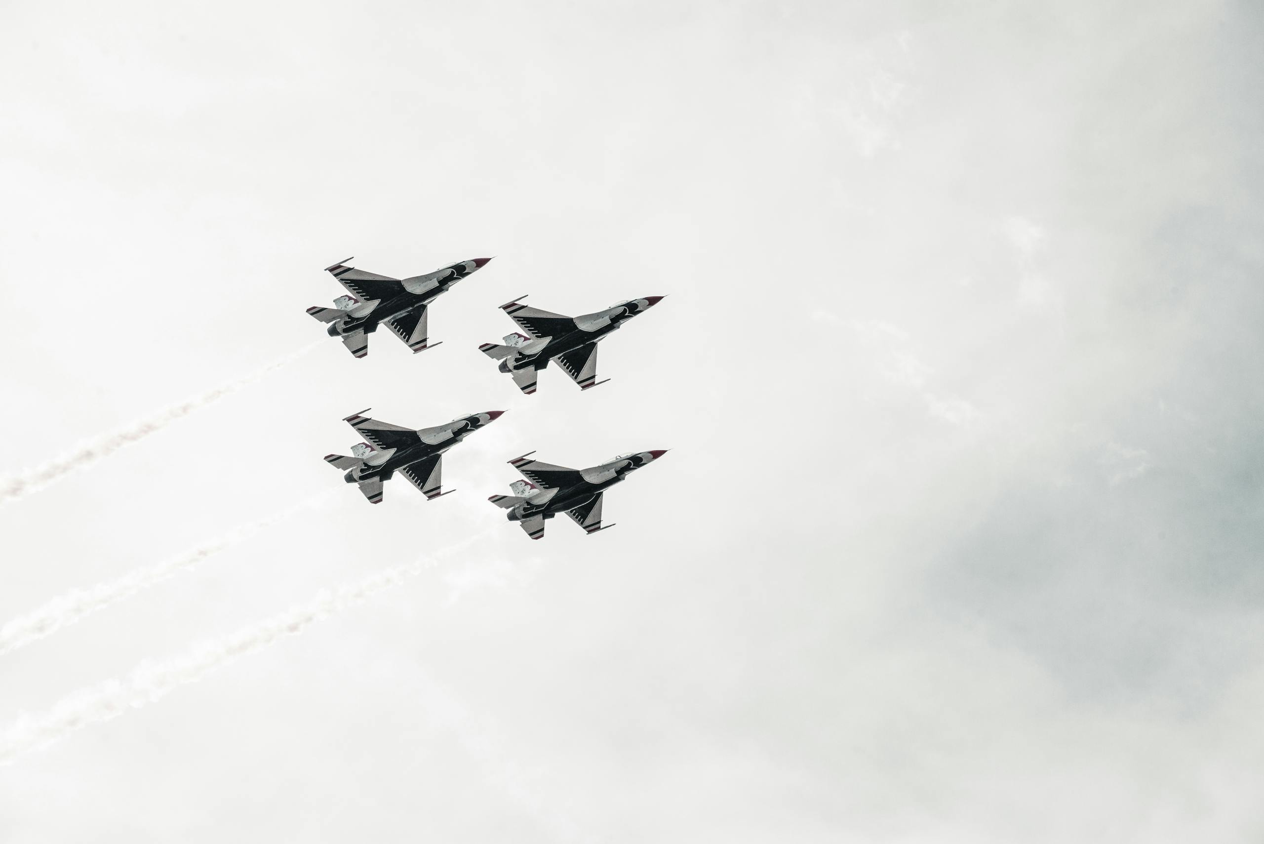 A squadron of fighter jets flying in formation against a cloudy sky.