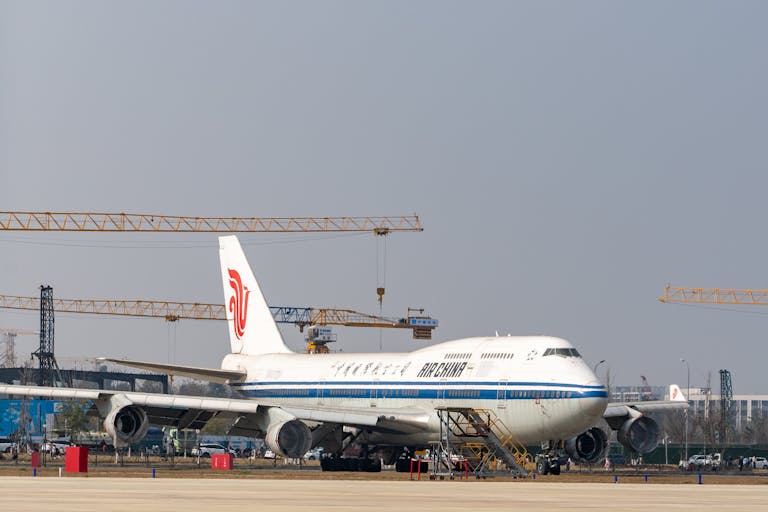 Air China Boeing 747 parked at an airport with construction cranes in the background.