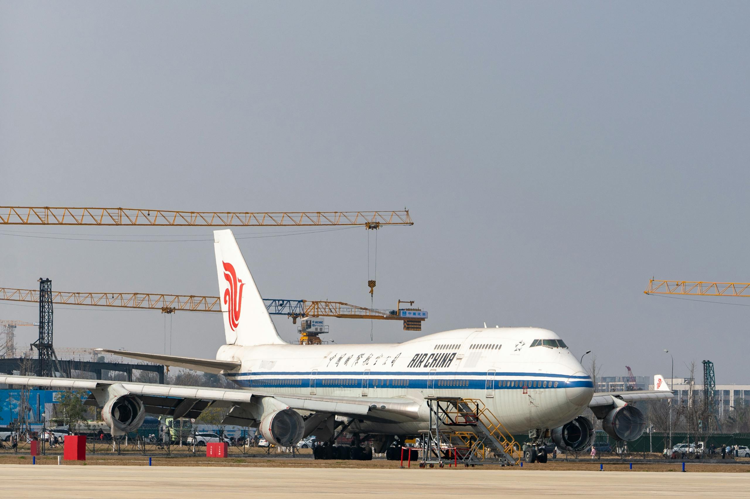 Air China Boeing 747 parked at an airport with construction cranes in the background.